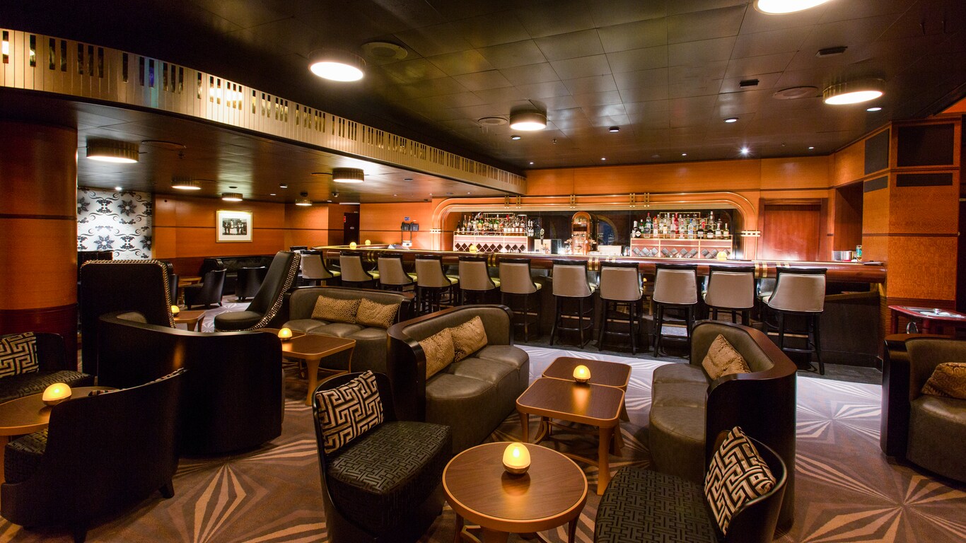 A large, spacious lounge features leather sofas, comfortable chairs and a long bar