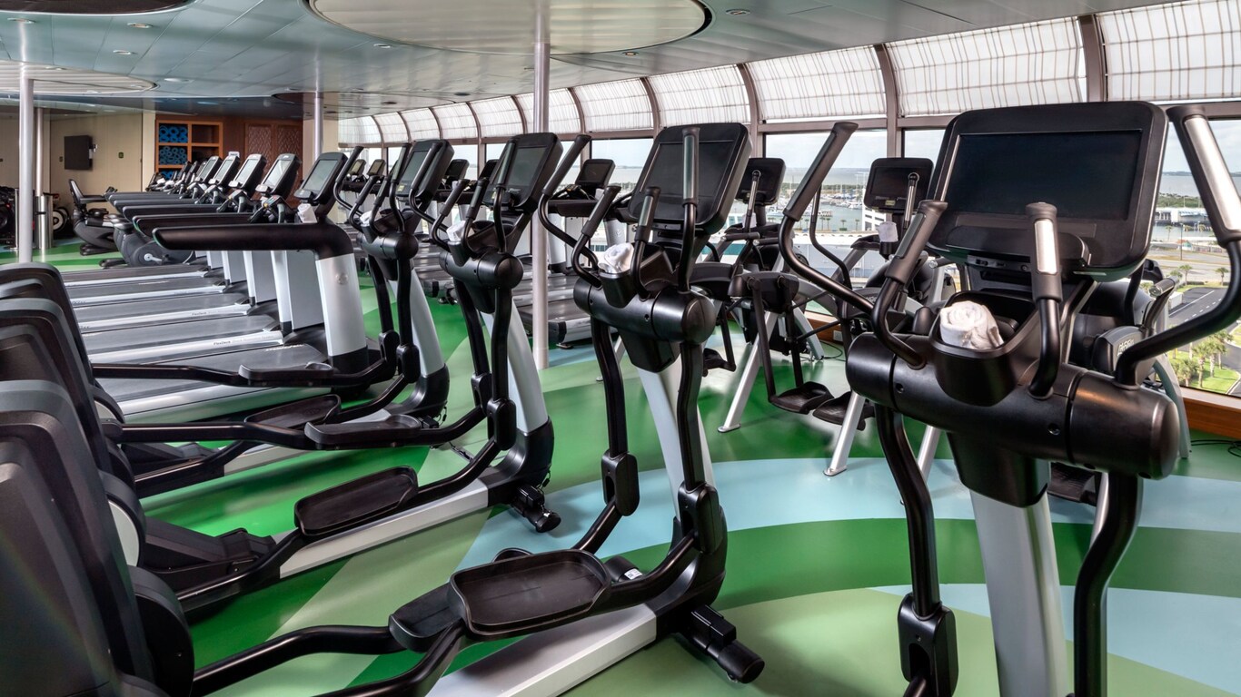 A row of treadmills and elliptical trainers in the fitness facility on a Disney ship