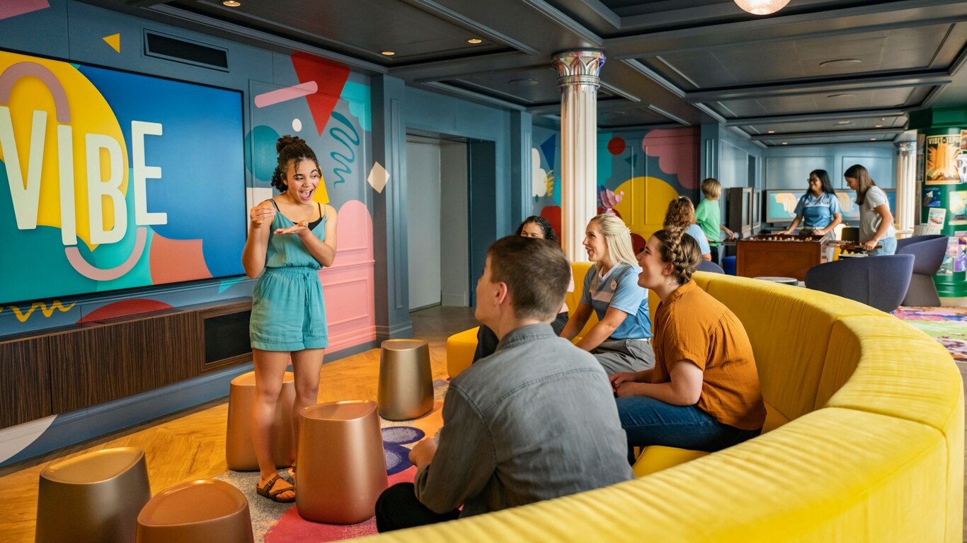 A group of teenagers playing a game of charades inside Vibe, a teen club on board the Disney Adventure