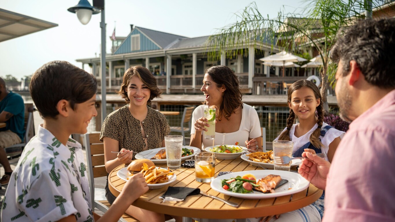 3 adults and 2 children enjoying themselves dining outdoors at Disney Resort Hotels & Disney Springs