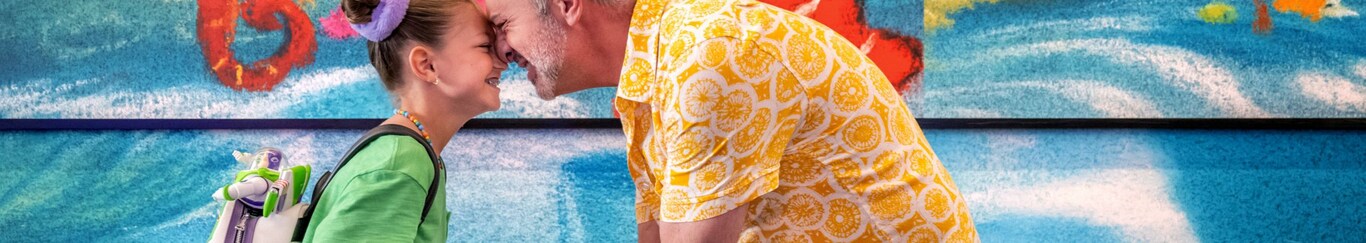 A father and daughter embracing and smiling by the Finding Nemo art wall at Pixar Place Hotel