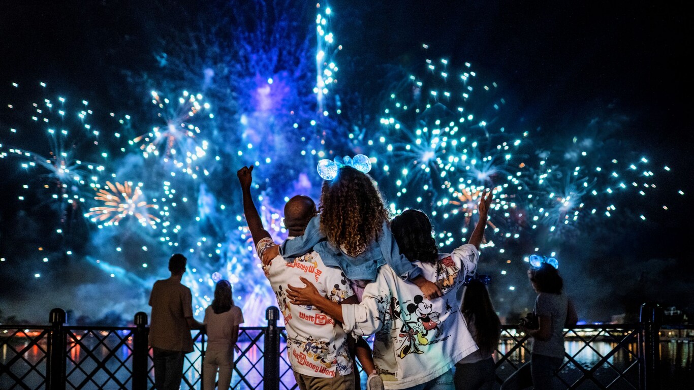 Dos padres con su hija pequeña en brazos viendo un espectáculo de fuegos artificiales en EPCOT