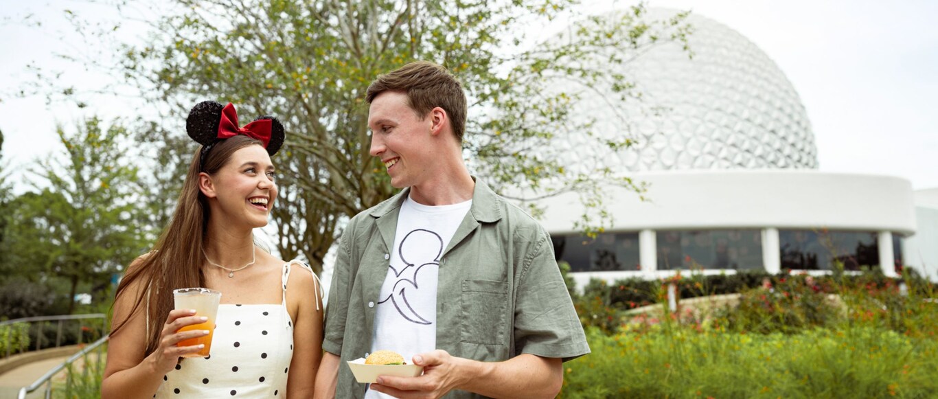 Two Guests enjoying food and beverages near the Spaceship Earth attraction in Epcot