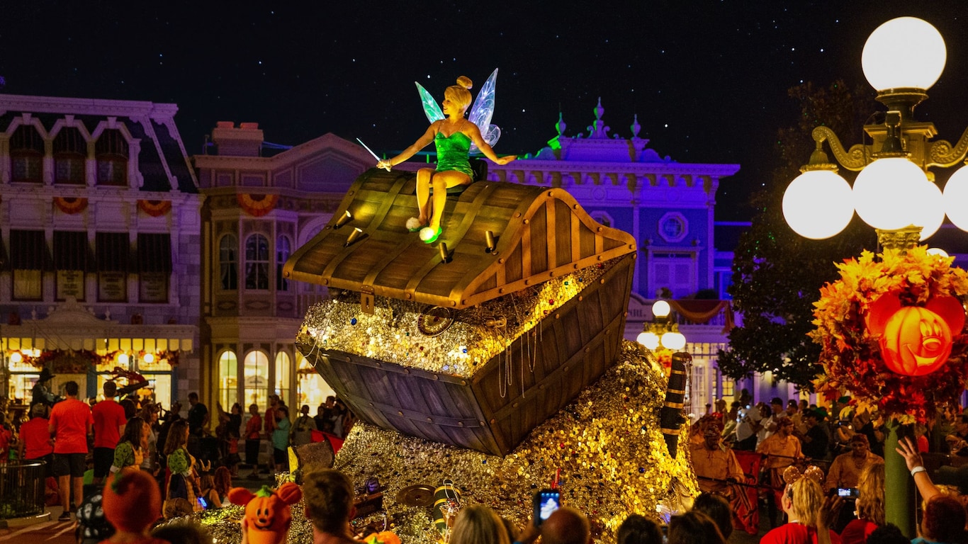 Tinker Bell perched atop a giant treasure chest on a parade float in the middle of Main Street, U S A