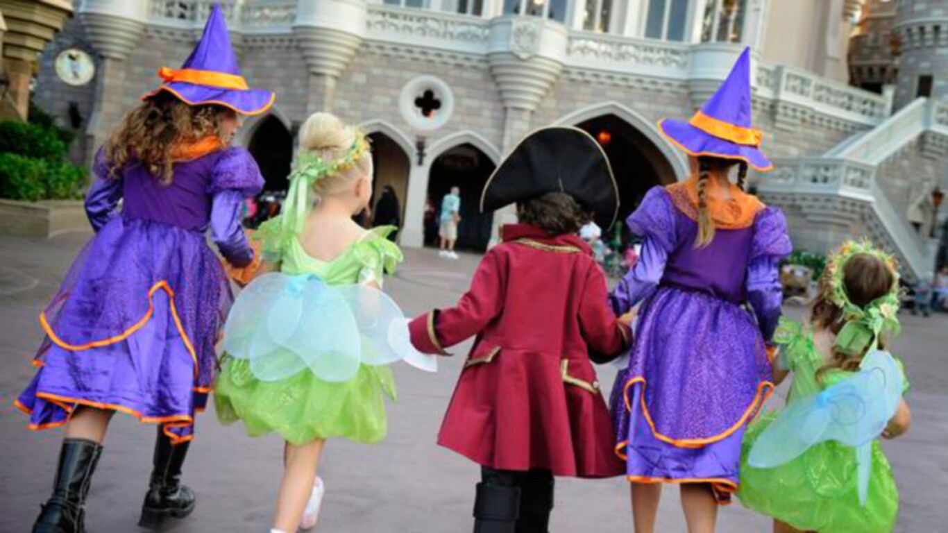 Several children dressed in Halloween costumes, walking toward Cinderella Castle
