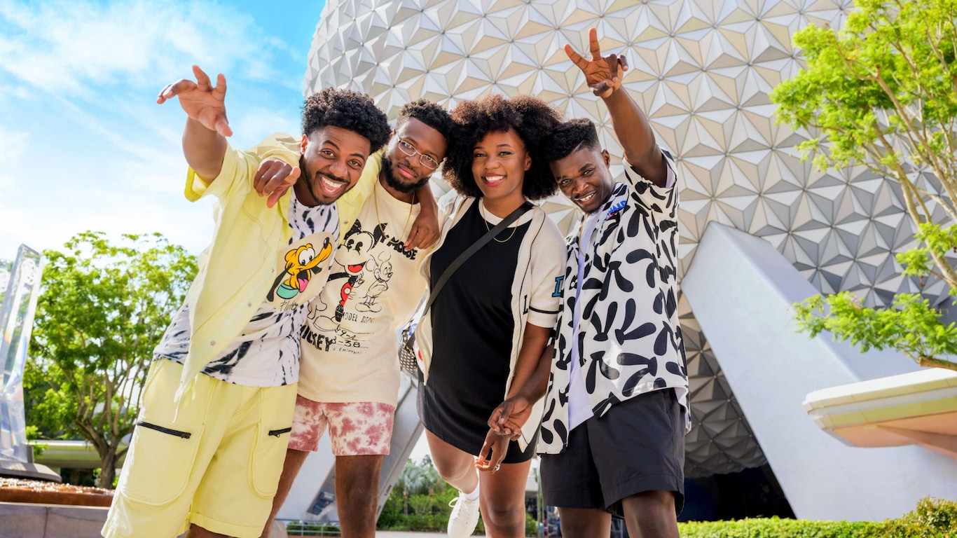 Four Guests posing for a photo in front of the Spaceship Earth attraction at Epcot