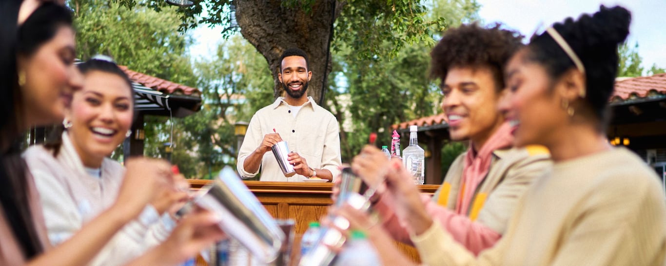 An instructor shows a group of seminar attendees how to mix a drink in a cocktail shaker