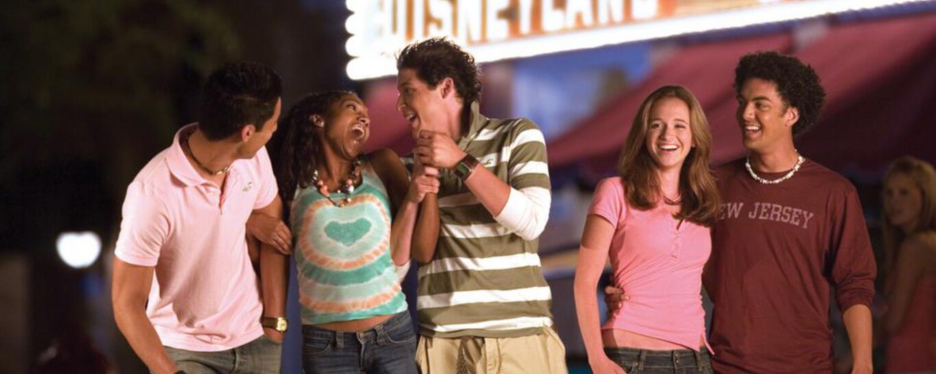A group of 5 young adults laugh and smile in front of the Emporium at Disneyland Park