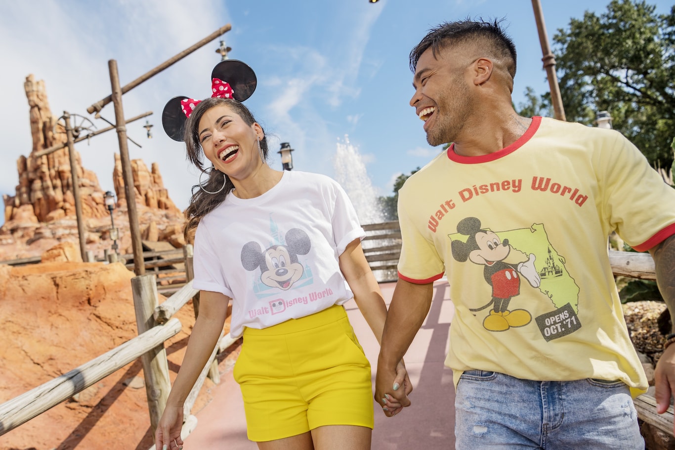 ウォルト・ディズニー・ワールド・リゾート、マジックキングダム・パークのビッグサンダー・マウンテンの近くを歩く、ミッキーマウスの Tシャツを着た笑顔の男女