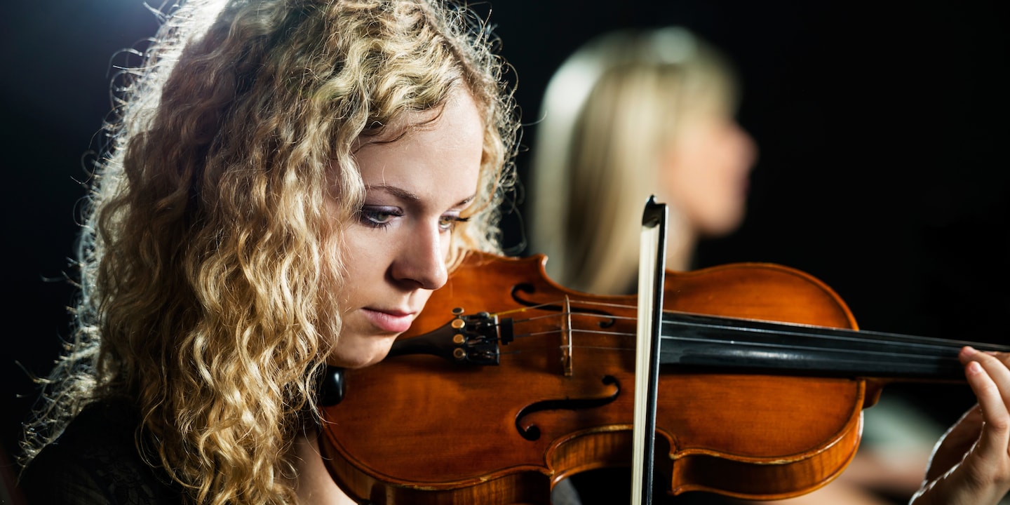A pretty teenage girl plays a violin