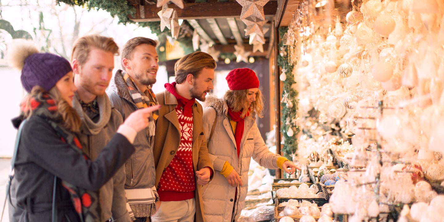 3 men and 2 women look at delicate ornaments at a Christmas Market
