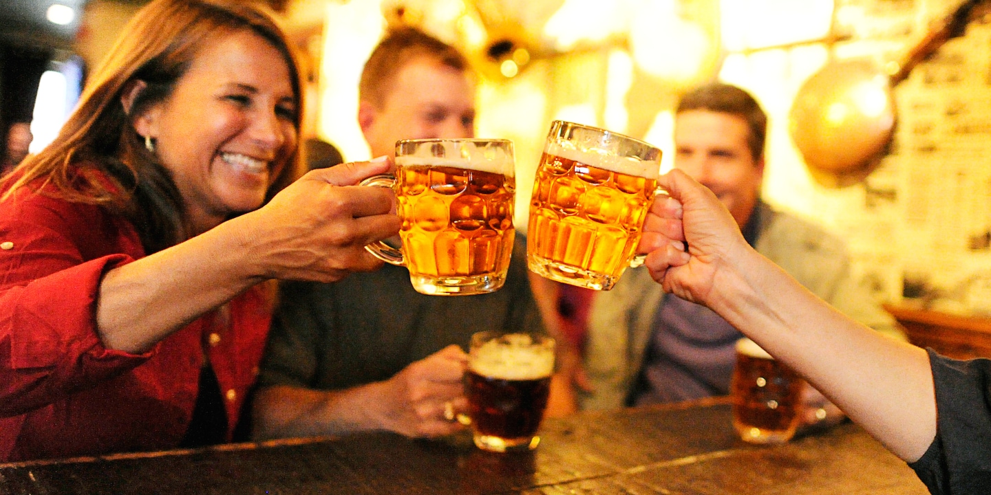 Two couples drinking beer in steins, with a woman toasting another woman Two couples drinking beer in steins, with a woman toasting another woman
