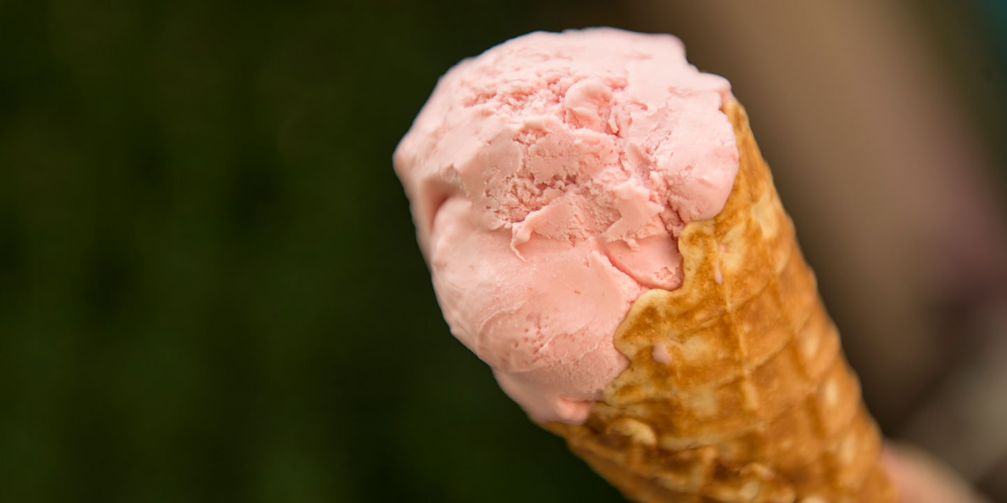 A scoop of strawberry ice cream inside a waffle cone A scoop of strawberry ice cream inside a waffle cone