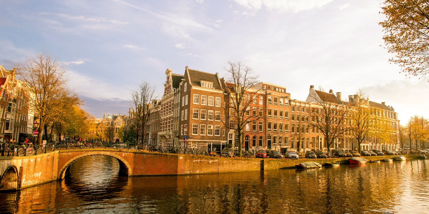 A stone bridge lined with bulidings spans a canal in Amsterdam