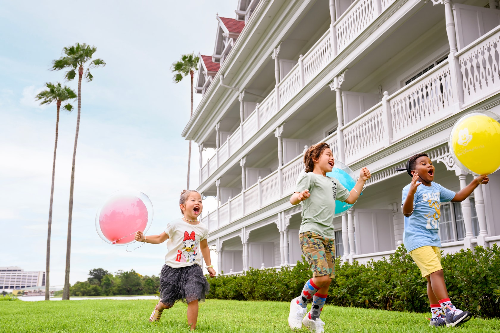 Three children running with balloons next to Disney's Grand Floridian Resort & Spa