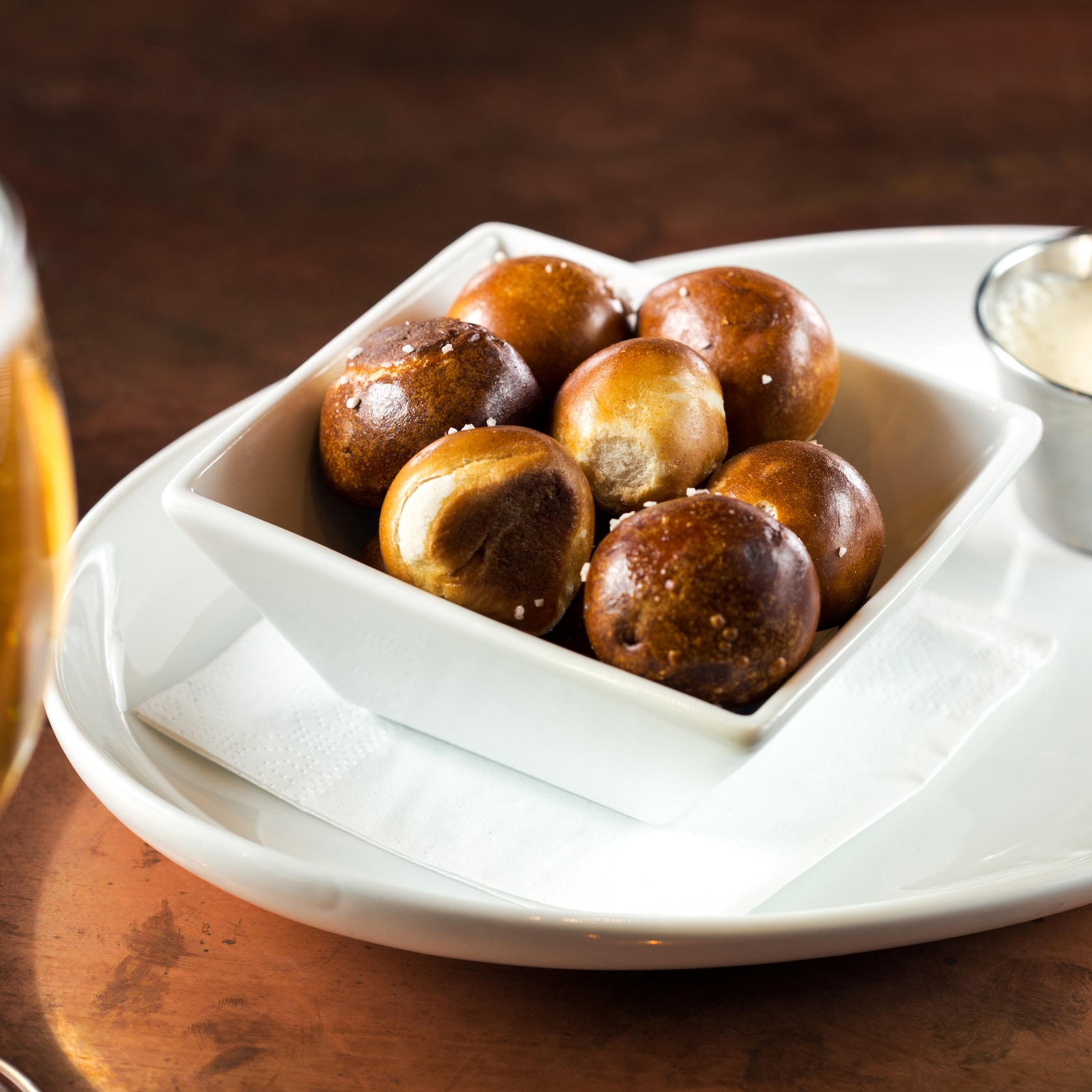 Drop in for happy hour and enjoy $7 bar bites and $2 off well drinks, local craft beers and glasses of wine (exclusions apply). slide 56 of 12 A glass of draft beer alongside a serving of Pretzel Bites and side of IPA Gouda Cheese Sauce