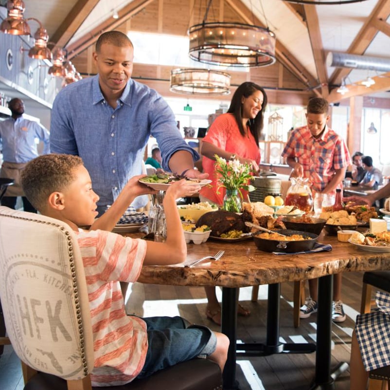 The best things in life—and from Chef Art’s kitchen—are meant to be shared. slide 34 of 7 A family enjoys a meal inside Chef Art Smith’s Homecomin’ as a server delivers a plate of food to the table