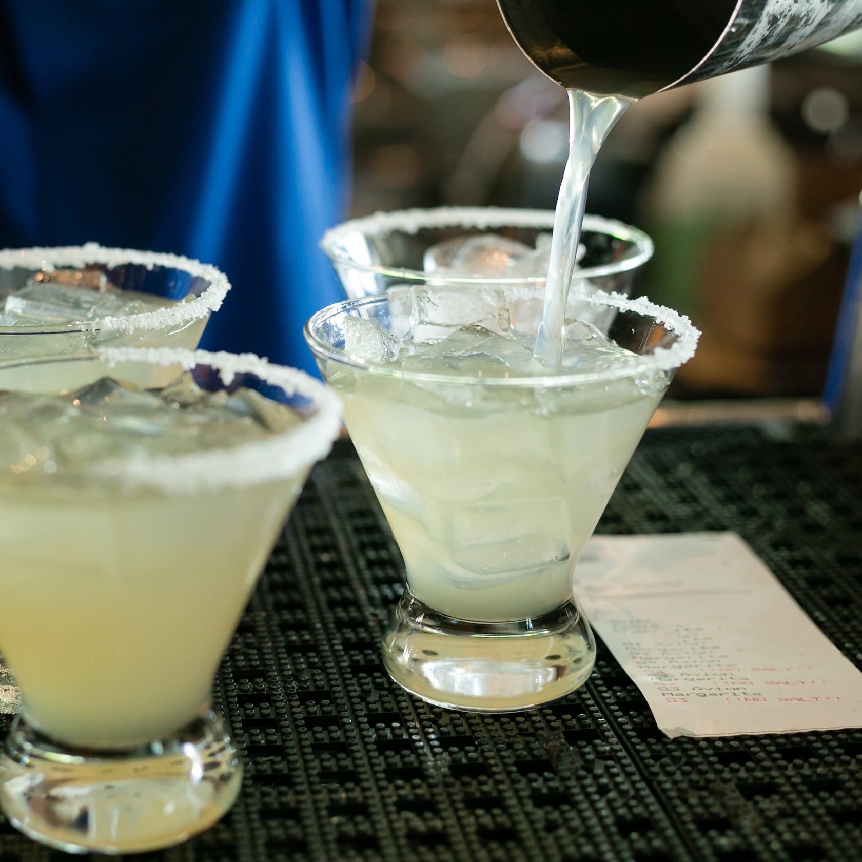 Choose from a stellar array of freshly made artisan margaritas, craft cocktails, agave flights and more. slide 74 of 16 A bartender pouring a freshly made margarita cocktail into glasses with ice and salted rims