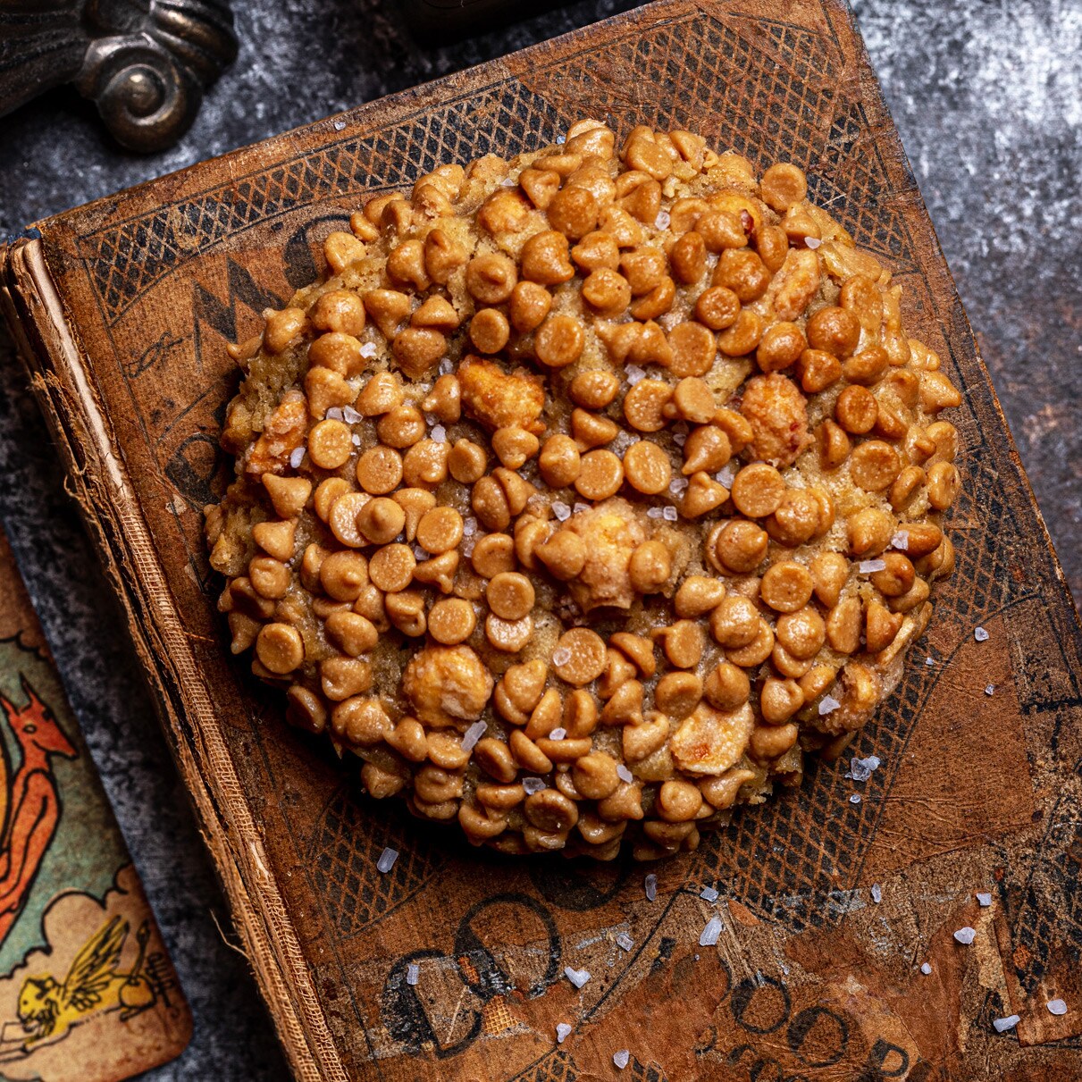 A Peanut Butter Cookie on an old cookbook surrounded by tarot cards