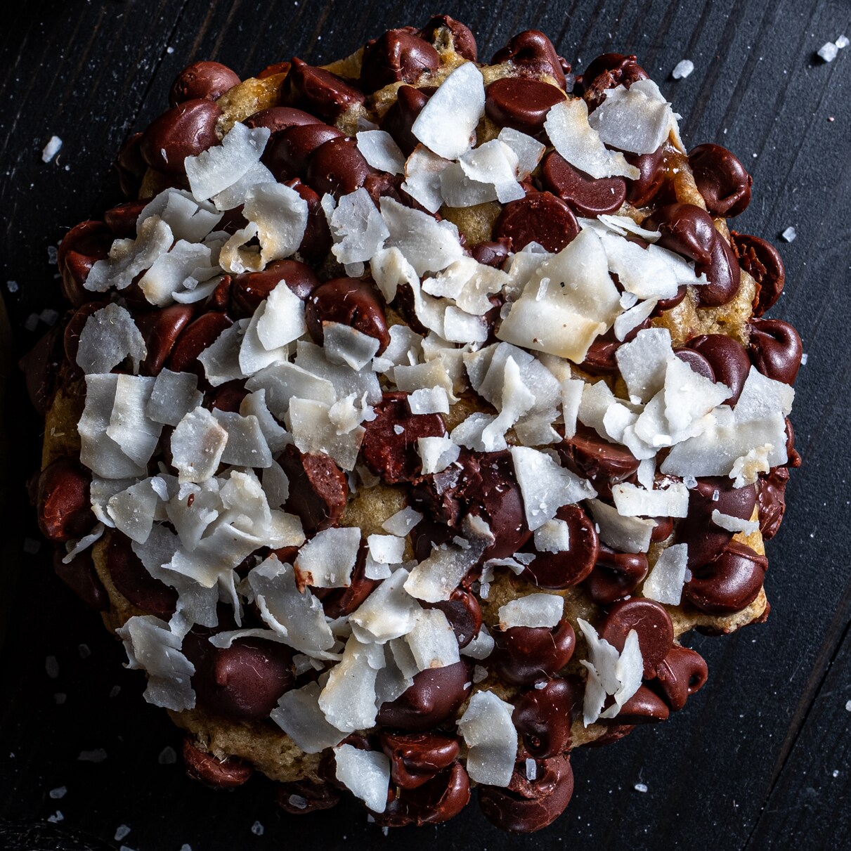 A chocolate chip cookie with large chocolate chips and flakes of coconut