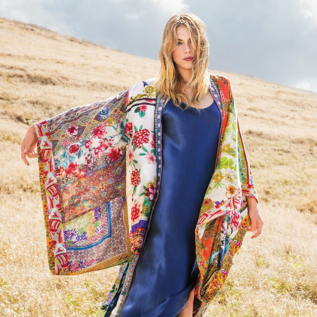 Una mujer en una pradera luce un vestido de seda y un chal con estampados de kimono de la boutique Johnny Was