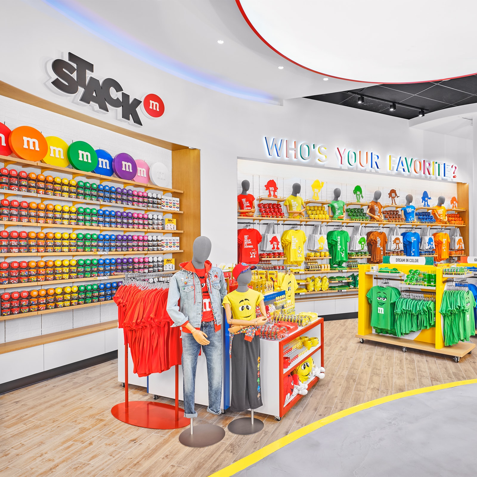 A store filled with M and M merchandise, including shirts, jackets, mugs and packages of candy. Various signs read Who’s Your Favorite, Dream in Color, Gotta Have M, and M Disney Springs.