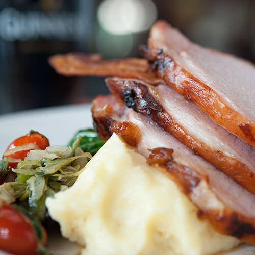 Glazed loin of bacon with braised cabbage, mashed potato and parsley cream sauce