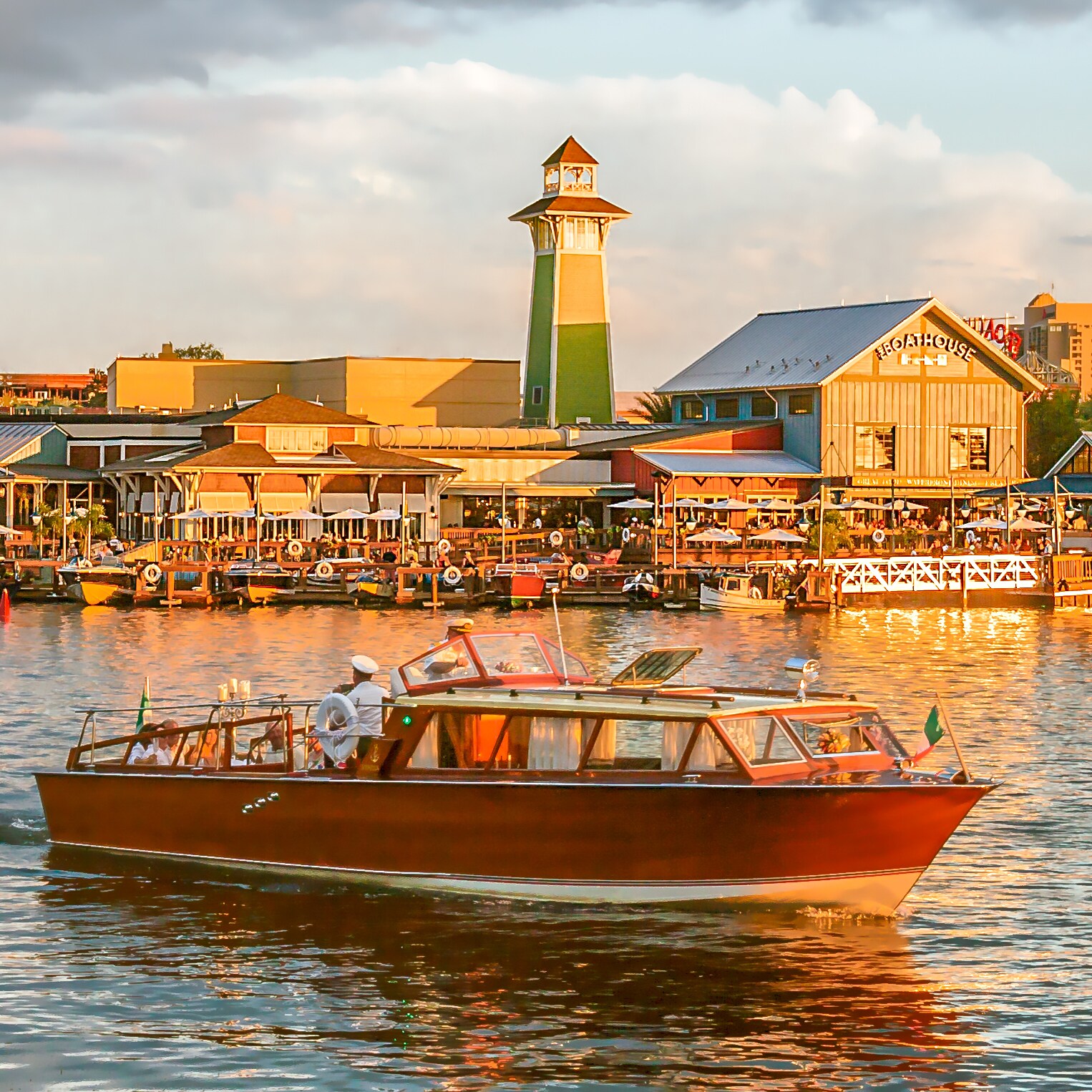 A small ship sails along the water in front of The BOATHOUSE at Disney Springs