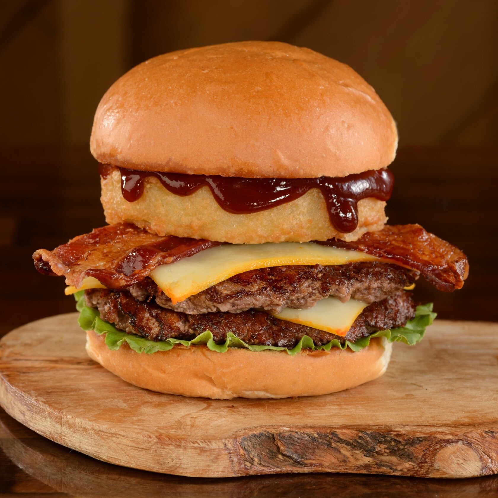 La Hamburguesa BBQ en D-Luxe Burger, con hamburguesa de carne cubierta con aros de cebolla empanizados, queso, tocino, salsa BBQ y lechuga, todo servido entre 2 panes