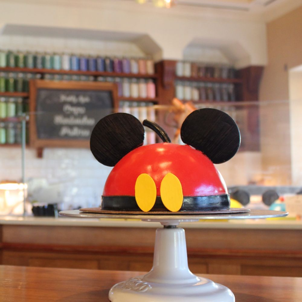 A Mickey Mouse dome cake atop a cake plate in Amorette's Patisserie at Disney Springs