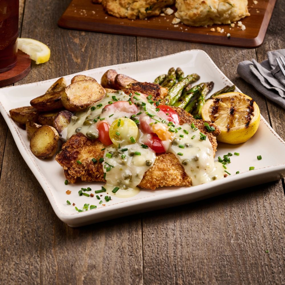 Enjoy delicious entrees prepared with the care of home cooking. slide 30 of 7 A dinner platter with a fried chicken cutlet topped with garlic, caper and gravy, served with potatoes and asparagus