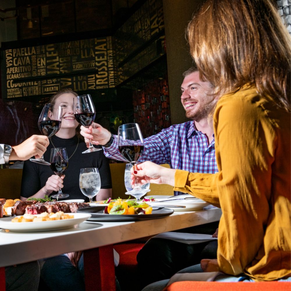 4 friends toasting with wine glasses and having a nice dinner at Jaleo by José Andrés