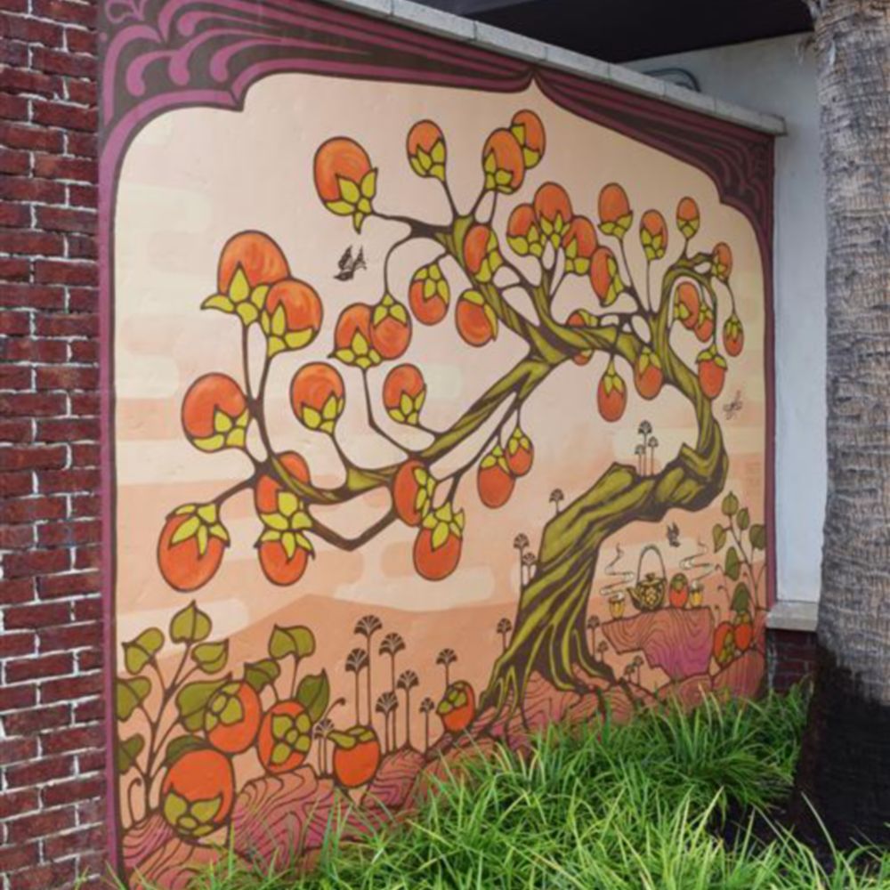 An outdoor mural of a whimsical tree full of oranges