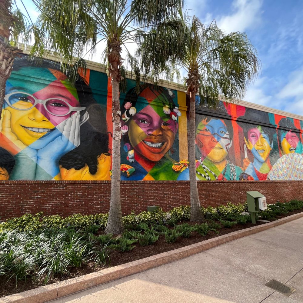 A mural on a brick wall featuring realistic images of children
