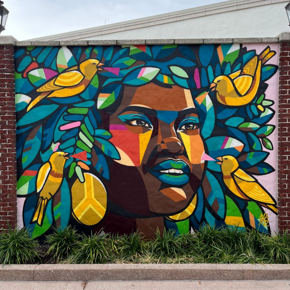 A mural of a woman’s face surrounded by 4 birds