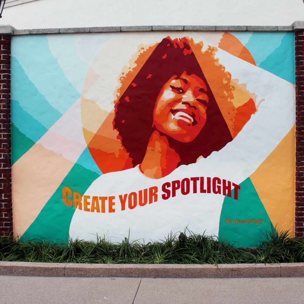 A mural of a smiling woman and the words, ‘Create Your Spotlight’