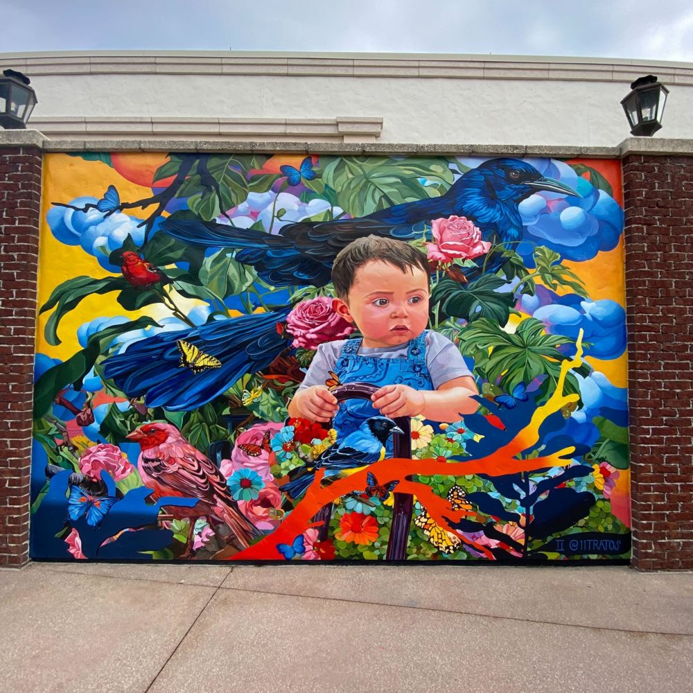 A mural of a little boy sitting among plantlife, birds and butterflies