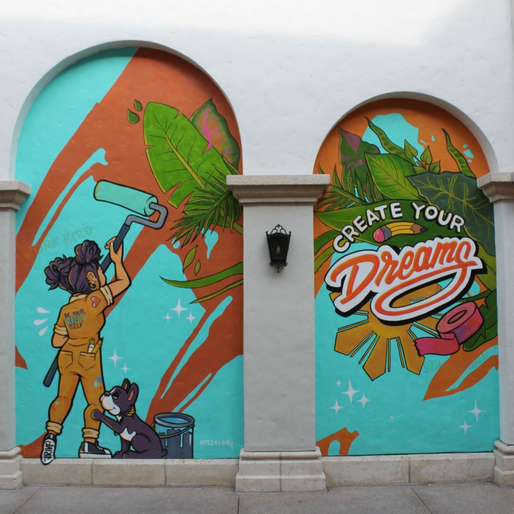 A mural of a puppy watching a girl painting 