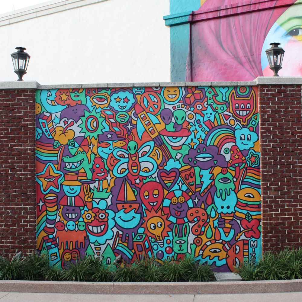A mural of rockets, rainbows and other shapes on a brick wall
