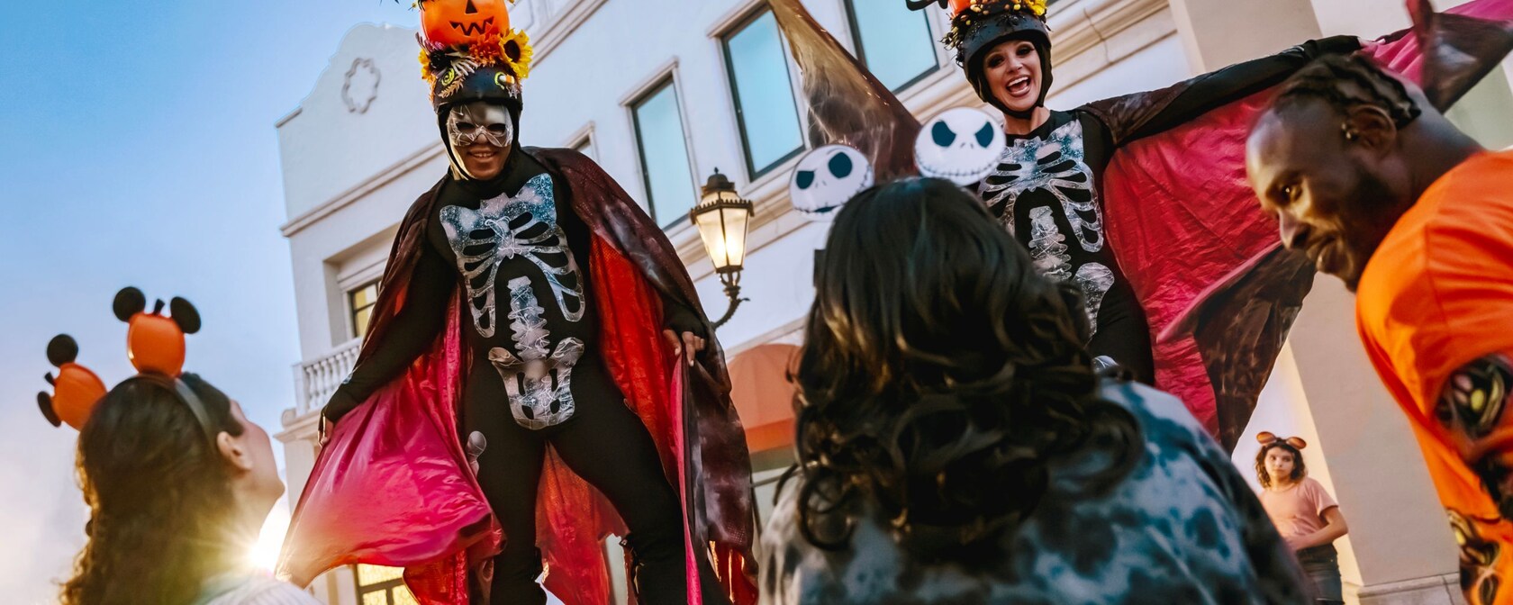 Halloween themed stilt walkers in skeleton costumes and pumpkin headpieces at Disney Springs