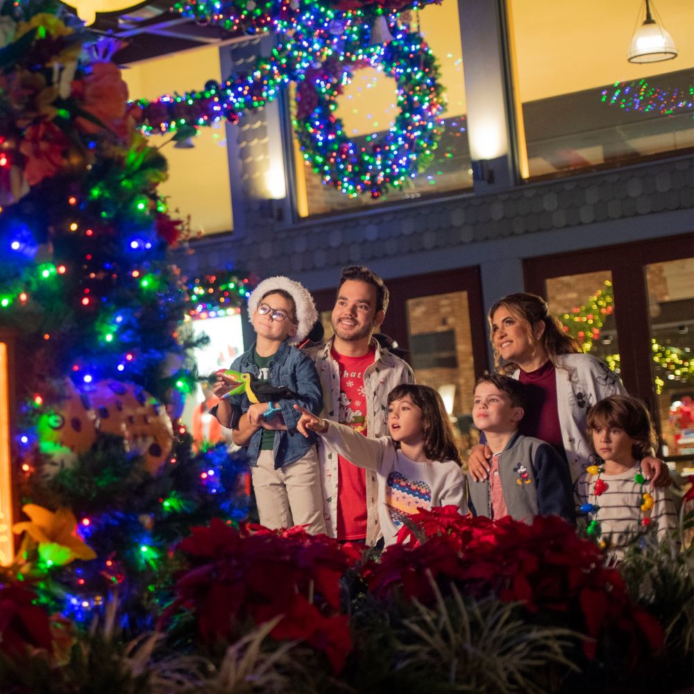 Two parents and their 4 kids look at a large Christmas tree