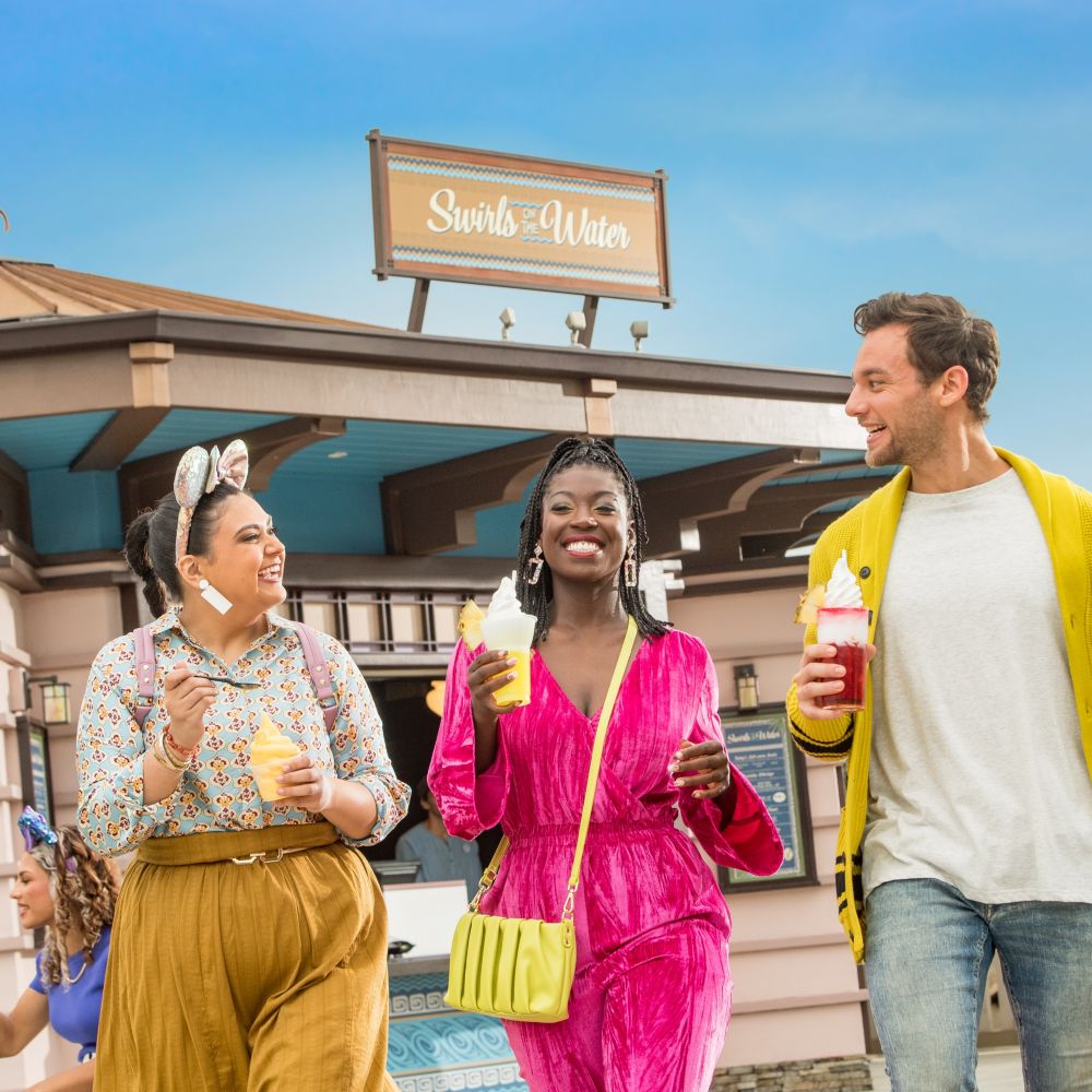A group of 3 friends walking down Disney Springs while enjoying desserts from Swirls on the Water