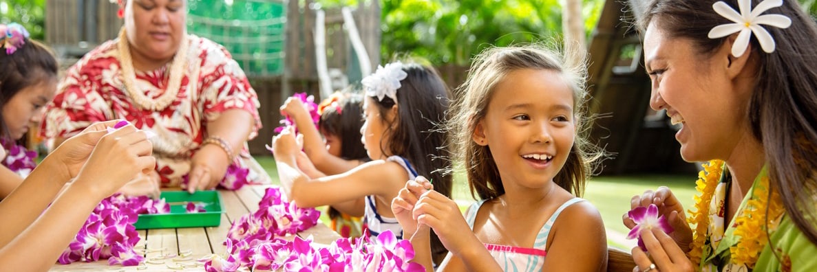 Cast Members lead several young girls in a lei-making activity
