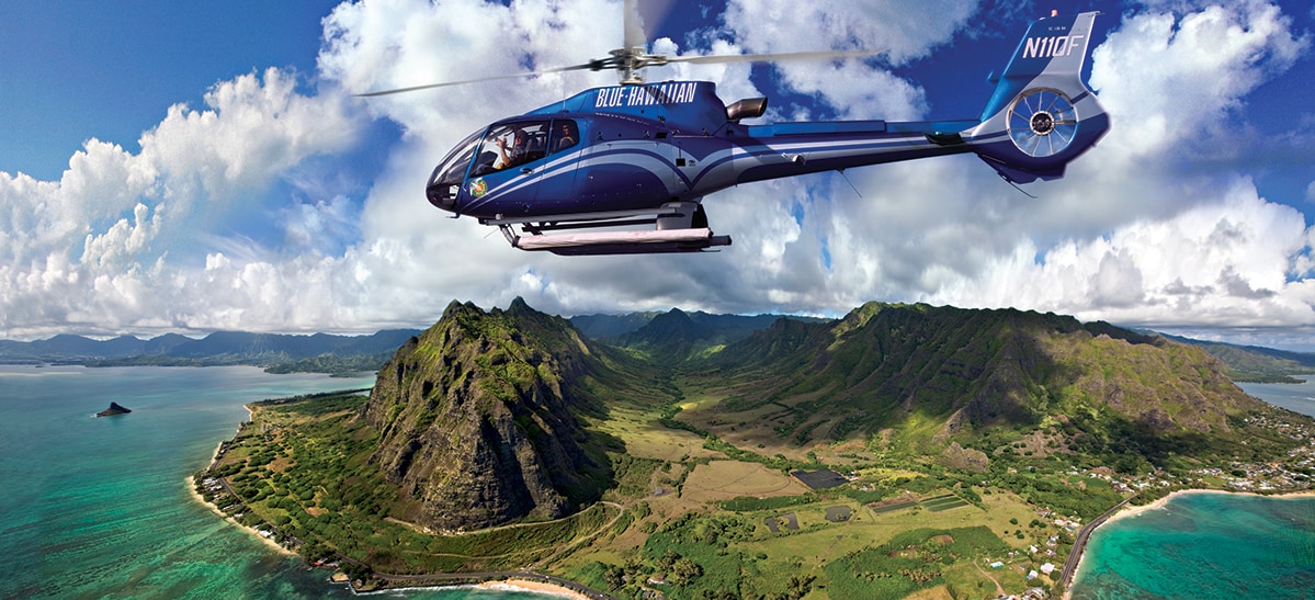 A helicopter named Blue Hawaiian flies above the lush island of Oahu and one of its shorelines