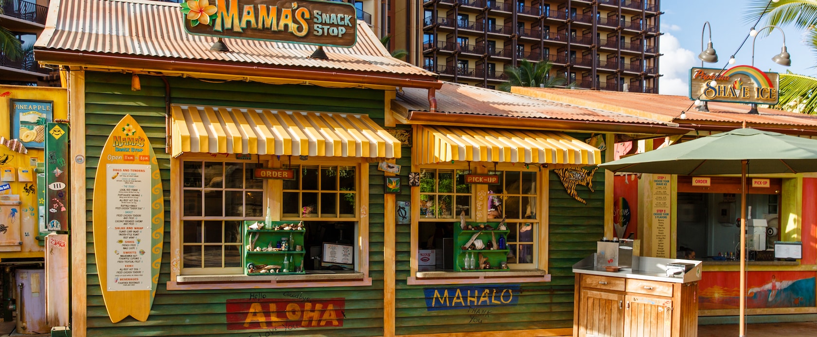 The exterior of Mama's Snack Stop, a quick-service venue with weathered green paint and yellow-striped awnings