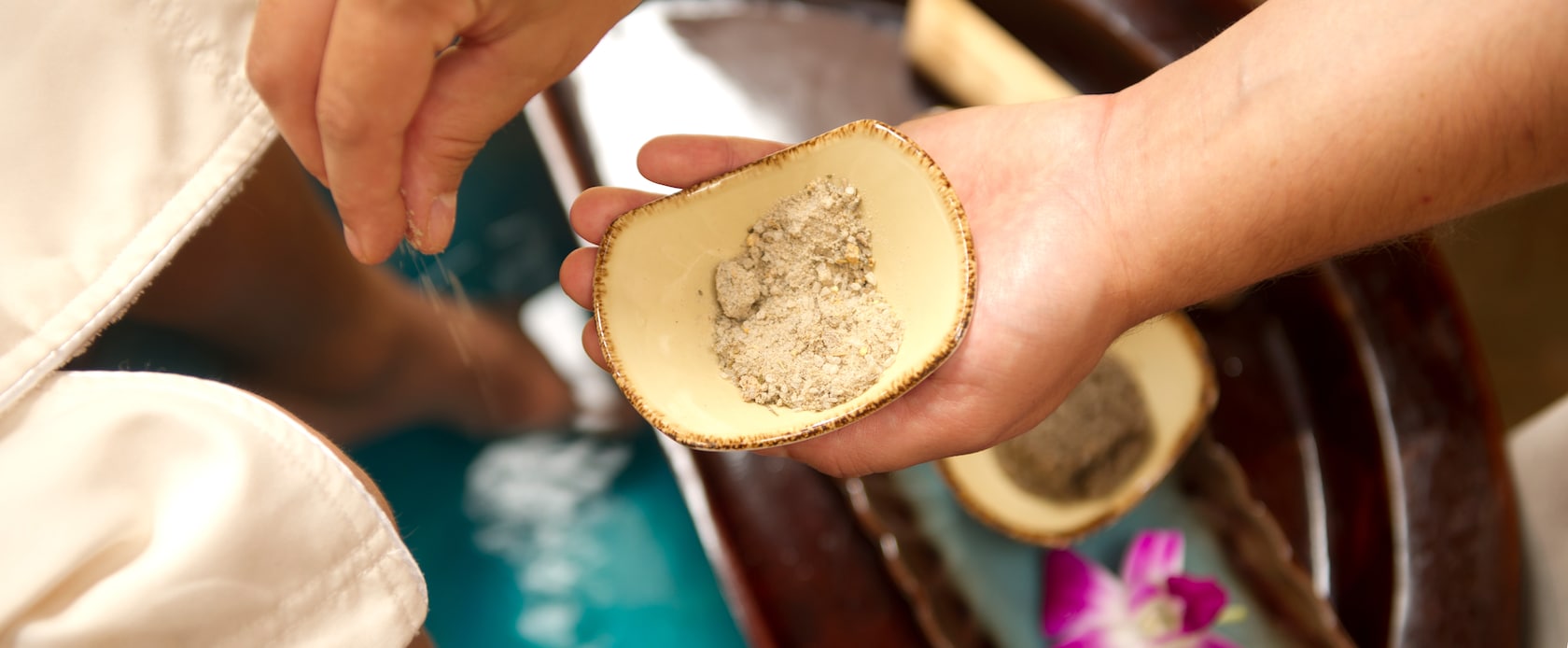 Male hands sprinkling exfoliating salts and aromatics into a small bowl