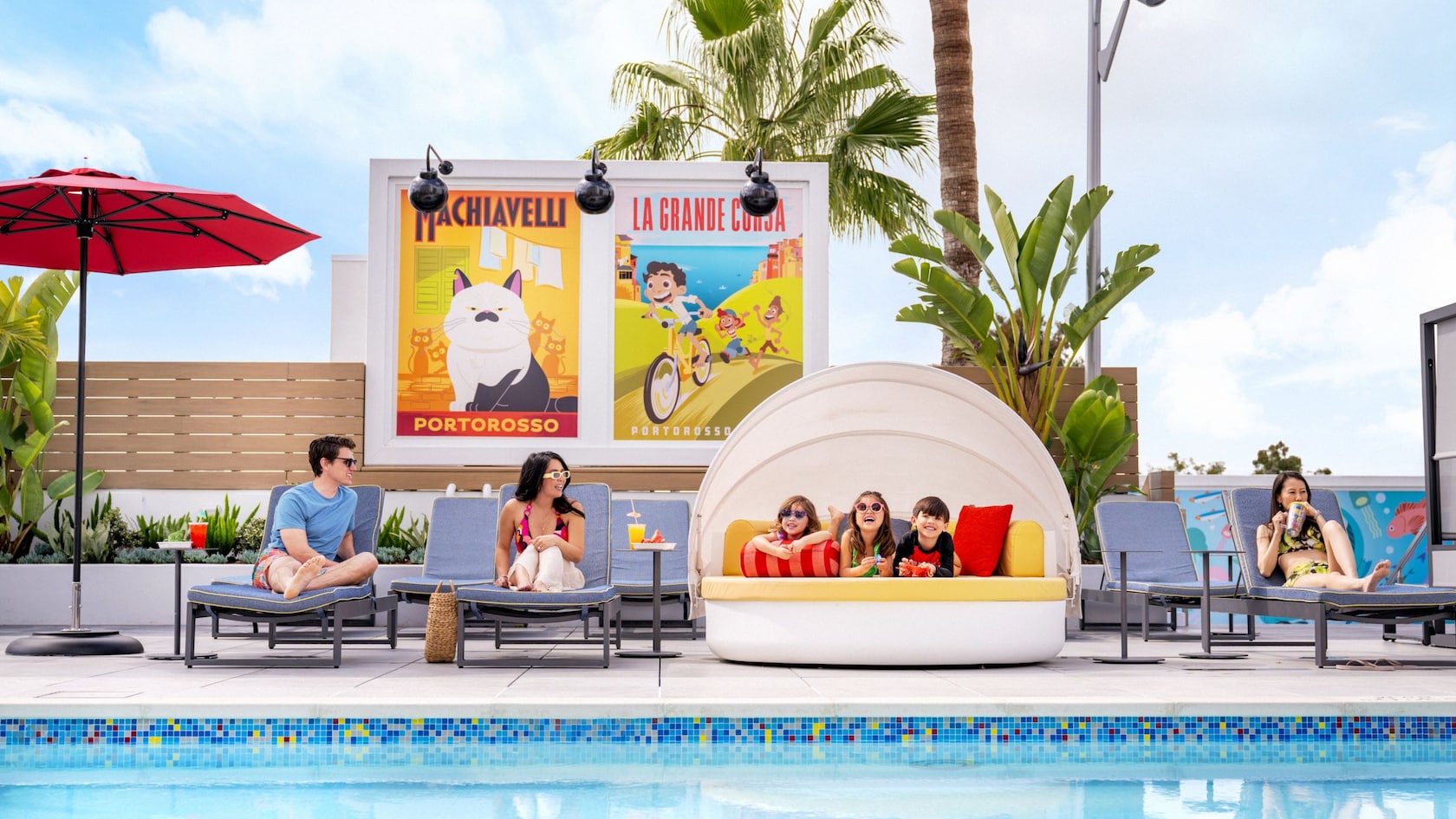 En el área de la piscina Pixel Pool de la azotea de Pixar Place Hotel, adultos sentados en camastros y tres niños relajándose en una cama de día, rodeados de llamativas obras de arte que representan historias de Pixar