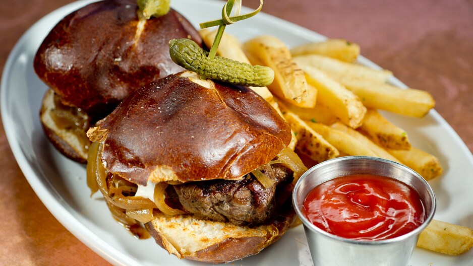 Mini-hambúrgueres de filé-mignon servidos com um picles, batata frita com salsa ao azeite de oliva e acompanhamento de ketchup