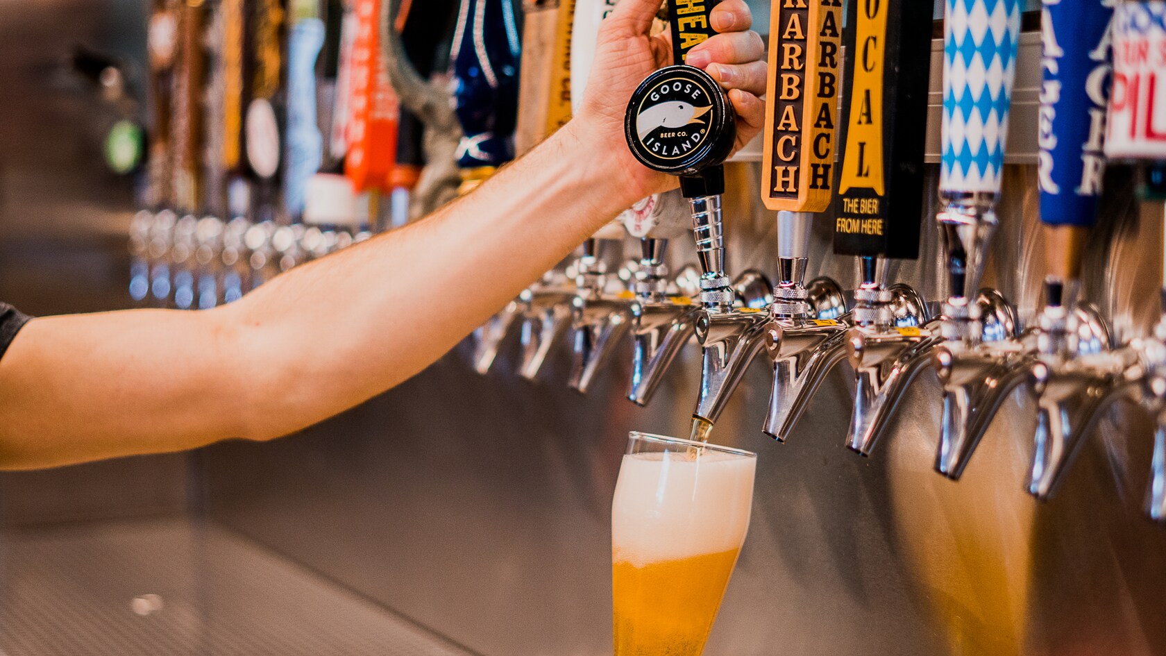 Um barman puxando uma alavanca para servir um copo de cerveja