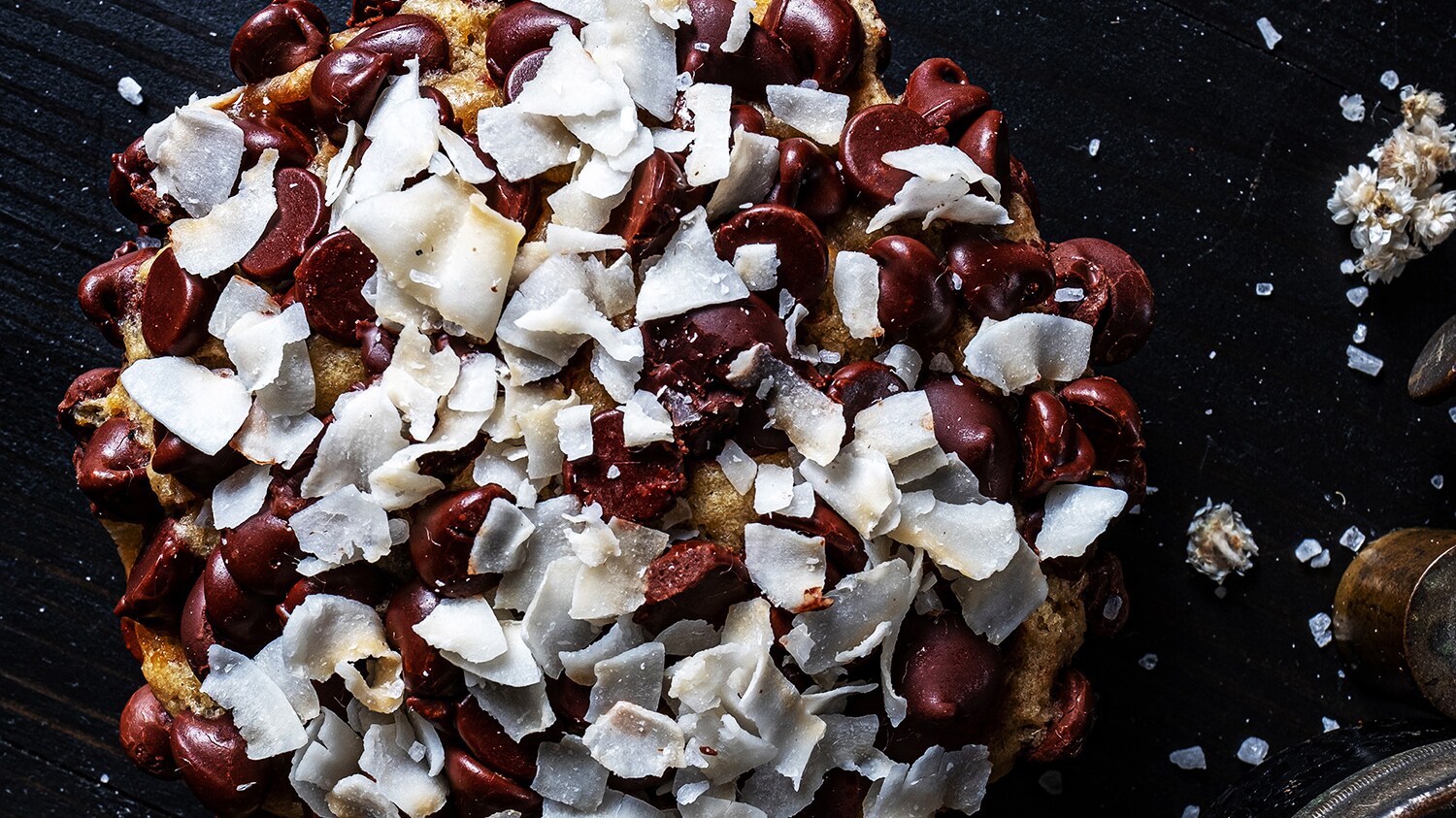 A chocolate chip cookie with large chocolate chips and flakes of coconut